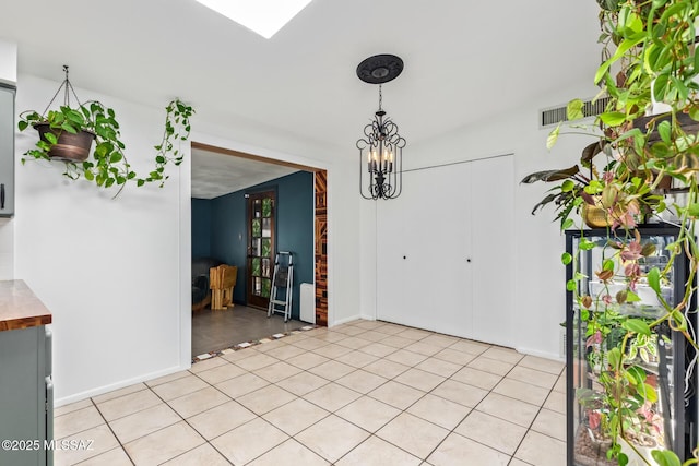 unfurnished dining area featuring visible vents, a notable chandelier, and baseboards