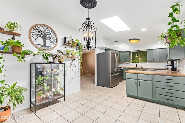 kitchen with a skylight, light tile patterned floors, tasteful backsplash, hanging light fixtures, and appliances with stainless steel finishes