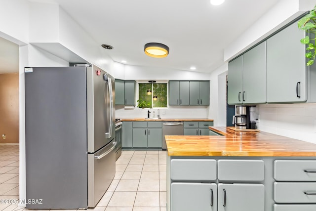 kitchen featuring stainless steel appliances, wooden counters, a peninsula, and light tile patterned floors