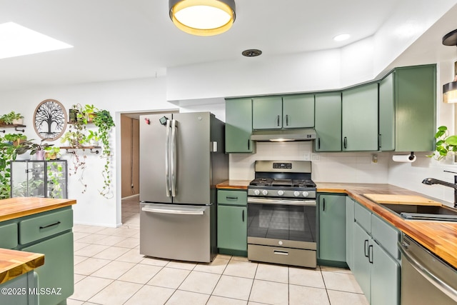 kitchen featuring wooden counters, appliances with stainless steel finishes, green cabinetry, and under cabinet range hood