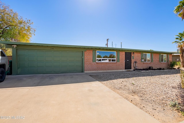 single story home with concrete driveway, brick siding, and an attached garage