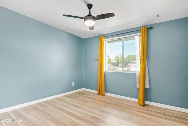 spare room with light wood-type flooring, a ceiling fan, and baseboards