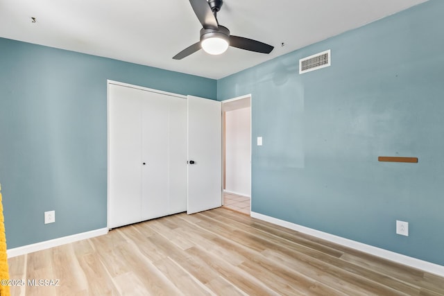 unfurnished bedroom featuring ceiling fan, wood finished floors, visible vents, baseboards, and a closet