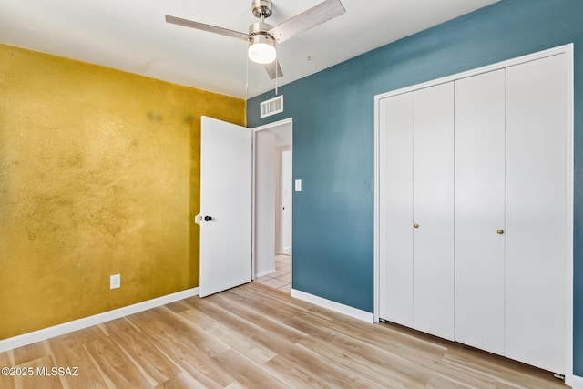 unfurnished bedroom featuring wood finished floors, a ceiling fan, visible vents, baseboards, and a closet