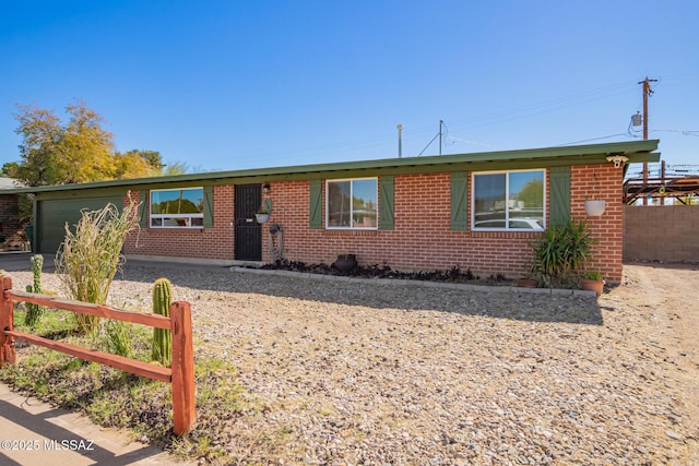 ranch-style home with brick siding, an attached garage, and fence