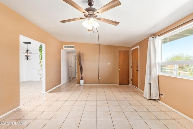 spare room featuring ceiling fan with notable chandelier, visible vents, baseboards, and light tile patterned floors