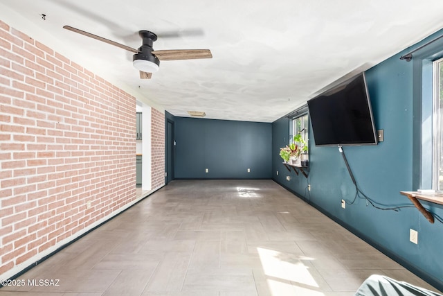 spare room featuring baseboards and brick wall