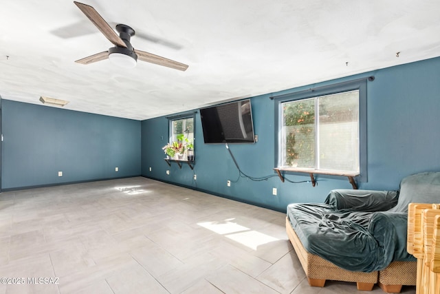 empty room featuring a wealth of natural light, ceiling fan, and baseboards