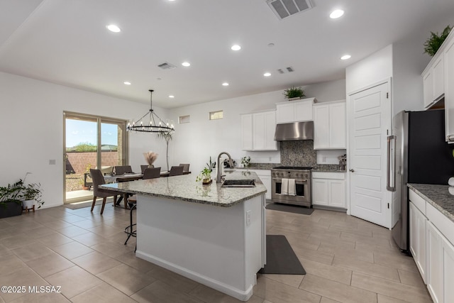 kitchen with visible vents, decorative backsplash, stainless steel appliances, under cabinet range hood, and a sink