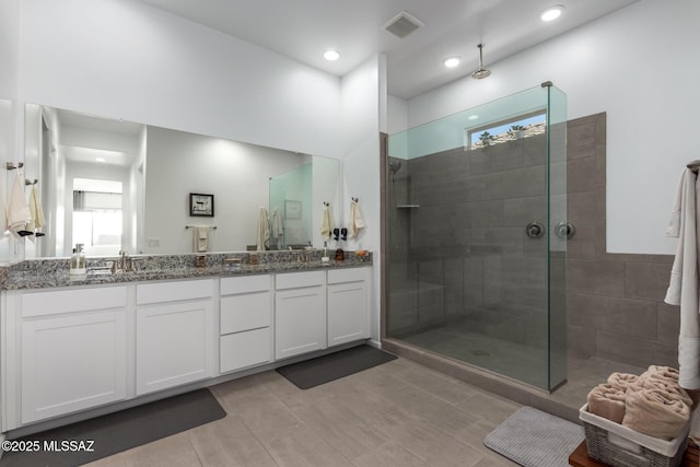 bathroom featuring double vanity, recessed lighting, visible vents, a sink, and walk in shower