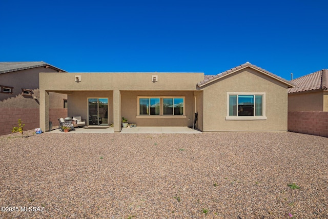 rear view of property with a tile roof, a patio area, a fenced backyard, and stucco siding