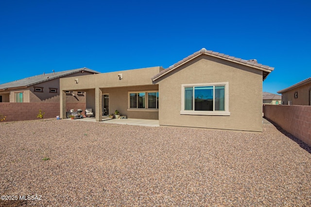 back of house with a patio, a tile roof, a fenced backyard, and stucco siding