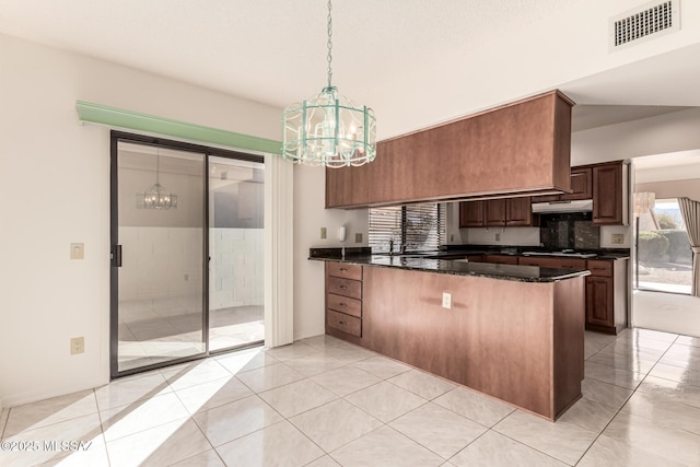 kitchen with visible vents, dark stone countertops, a peninsula, under cabinet range hood, and gas stovetop