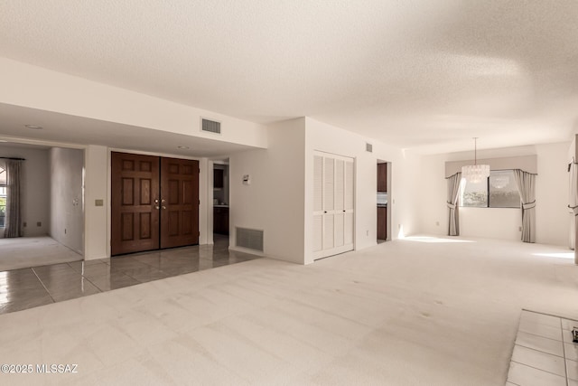 tiled spare room featuring carpet floors, visible vents, and a textured ceiling