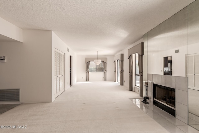 hallway featuring light carpet, visible vents, and a textured ceiling