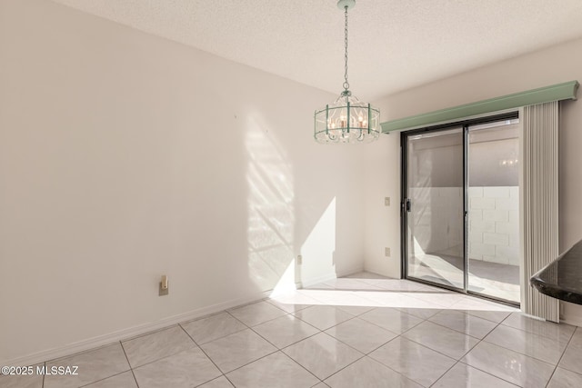 spare room with a chandelier, a textured ceiling, baseboards, and light tile patterned floors