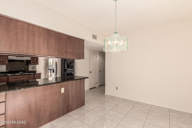 kitchen featuring black microwave, exhaust hood, visible vents, stovetop, and stainless steel fridge