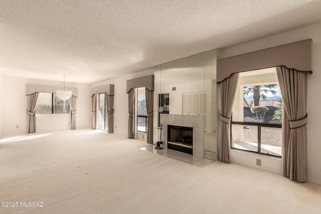 unfurnished living room featuring a textured ceiling, carpet, a fireplace, and a wealth of natural light