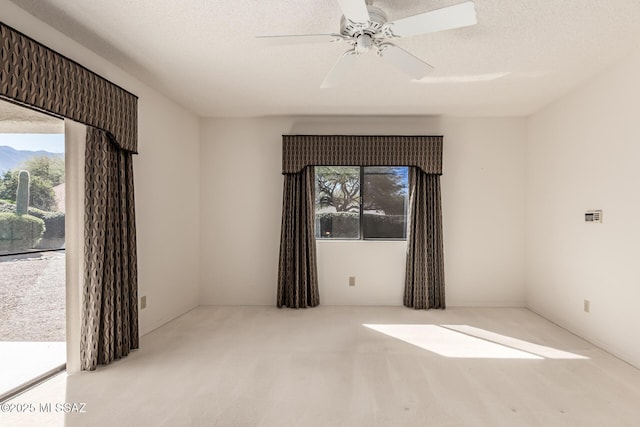 carpeted spare room featuring a ceiling fan and a textured ceiling