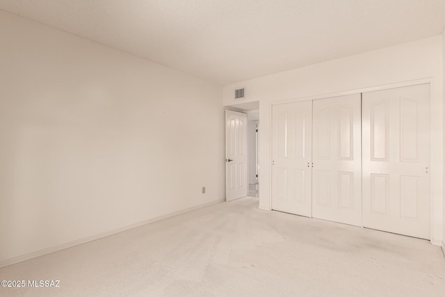 unfurnished bedroom with baseboards, a closet, visible vents, and light colored carpet