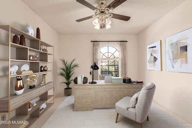 carpeted office space featuring a ceiling fan and a textured ceiling