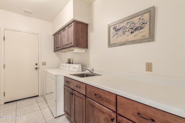 washroom featuring cabinet space, visible vents, light tile patterned flooring, a sink, and independent washer and dryer