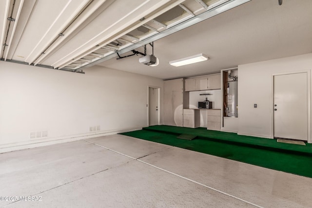 garage featuring water heater, visible vents, and a garage door opener