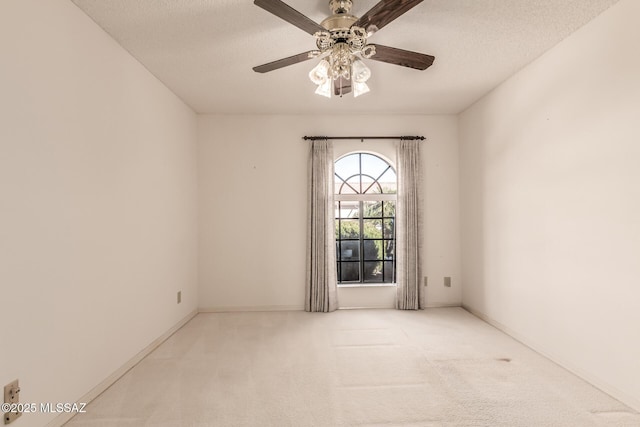 carpeted empty room featuring a textured ceiling, a ceiling fan, and baseboards