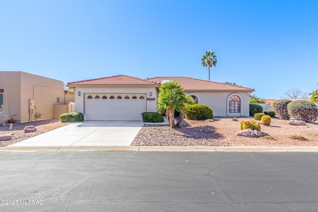 mediterranean / spanish-style house with a garage, a tile roof, concrete driveway, and stucco siding