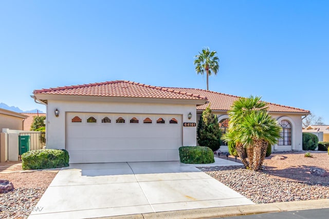 mediterranean / spanish home with driveway, a tile roof, a garage, and stucco siding