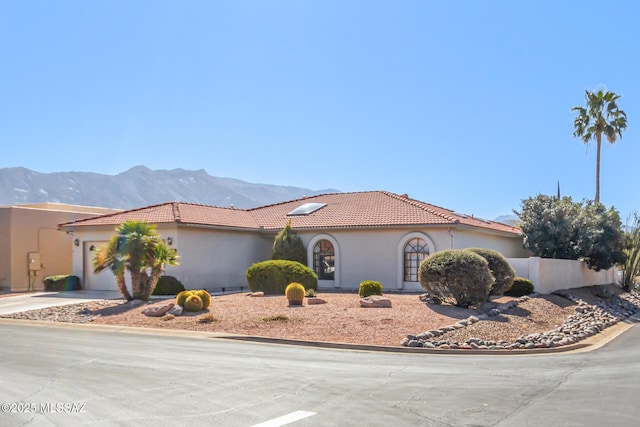 view of front of home featuring a garage, driveway, a tiled roof, a mountain view, and stucco siding