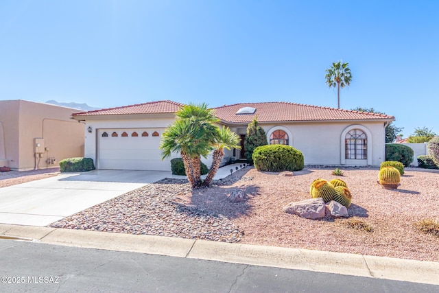 view of front of house featuring a tile roof, driveway, an attached garage, and stucco siding