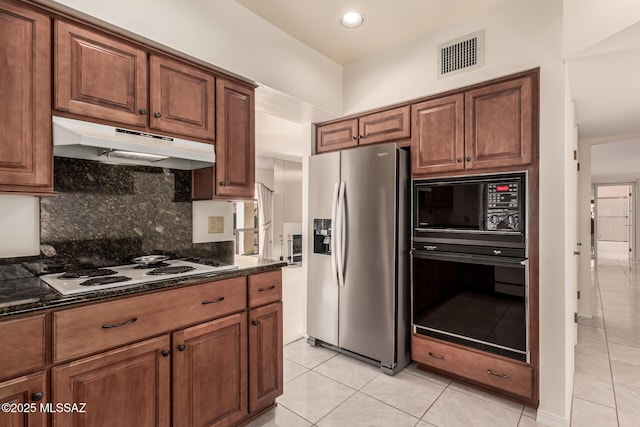 kitchen with light tile patterned floors, under cabinet range hood, visible vents, black appliances, and tasteful backsplash