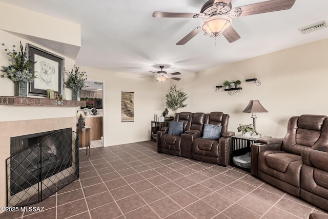 living room with a tile fireplace, visible vents, ceiling fan, and dark tile patterned floors