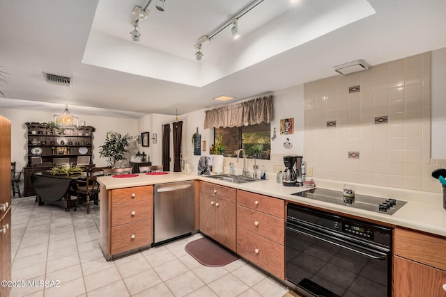 kitchen with light countertops, brown cabinetry, a sink, a peninsula, and black appliances