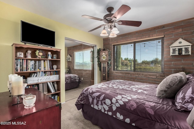 bedroom featuring a ceiling fan, light colored carpet, and brick wall