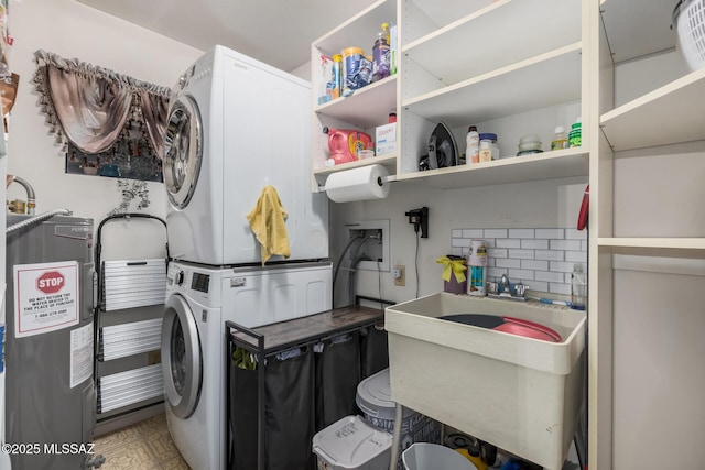 laundry area with stacked washer and dryer, water heater, laundry area, and a sink