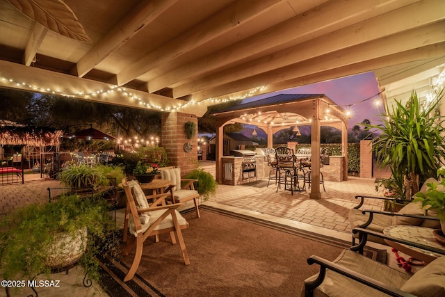 patio terrace at dusk featuring a gazebo, area for grilling, and fence