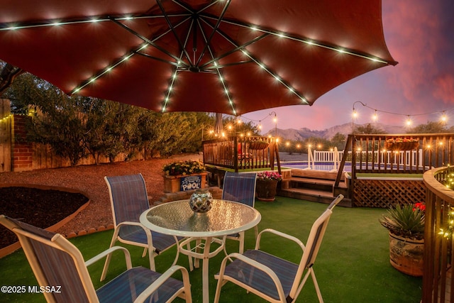 view of patio with outdoor dining space, fence, and a deck