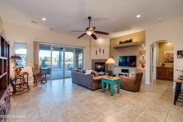 living room with visible vents, arched walkways, a ceiling fan, a glass covered fireplace, and recessed lighting