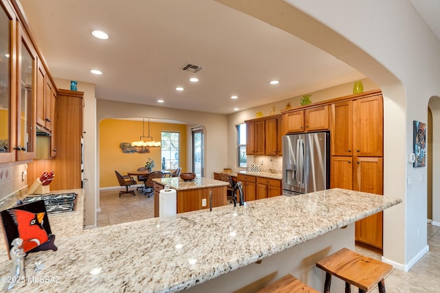 kitchen with arched walkways, stainless steel appliances, visible vents, backsplash, and a peninsula