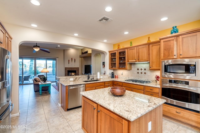 kitchen featuring arched walkways, stainless steel appliances, visible vents, open floor plan, and a sink