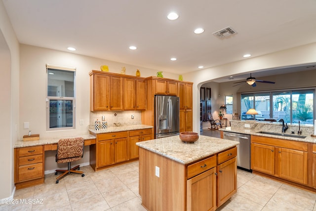 kitchen featuring arched walkways, stainless steel appliances, a sink, decorative backsplash, and a center island