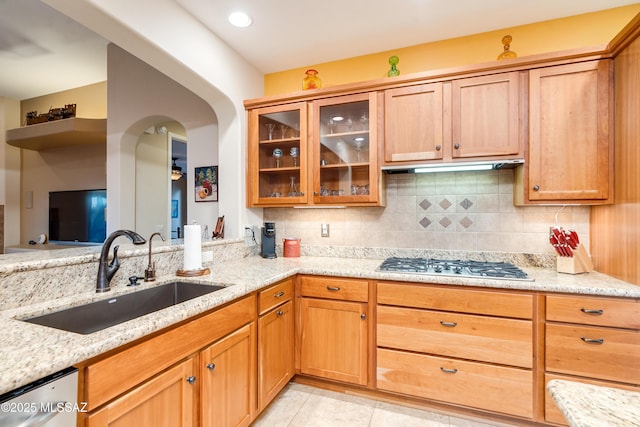 kitchen featuring stainless steel appliances, tasteful backsplash, a sink, and light stone countertops