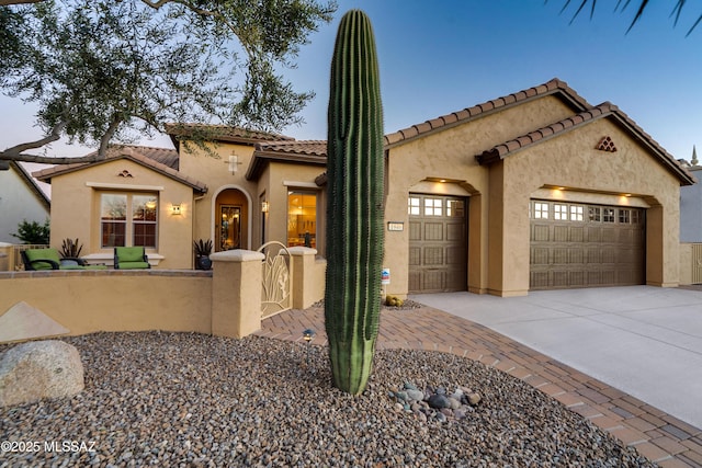 mediterranean / spanish house featuring a fenced front yard, a garage, concrete driveway, a tiled roof, and stucco siding