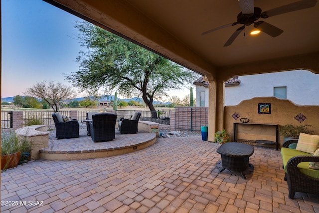 view of patio / terrace with an outdoor living space with a fireplace, outdoor dining space, fence, and a ceiling fan