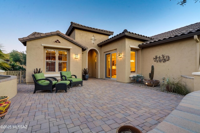 rear view of property featuring a tile roof, a patio, stucco siding, an outdoor hangout area, and fence