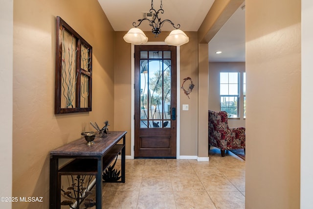 entrance foyer with a notable chandelier, baseboards, and light tile patterned floors