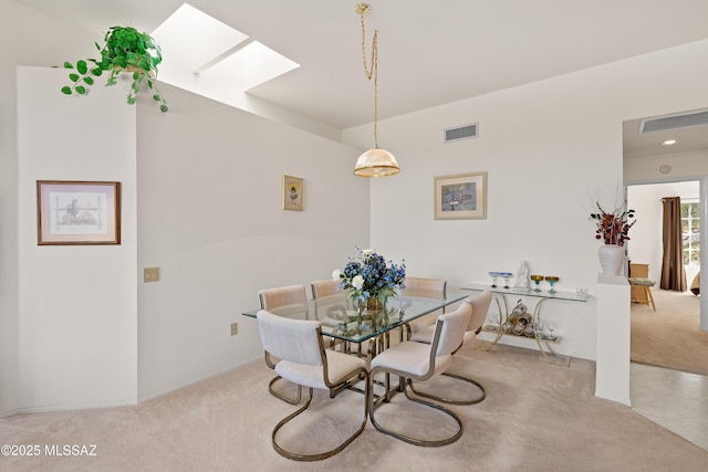 dining space with light carpet, a skylight, and visible vents