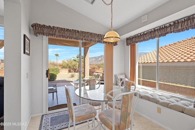 dining room with lofted ceiling, a healthy amount of sunlight, a mountain view, and baseboards